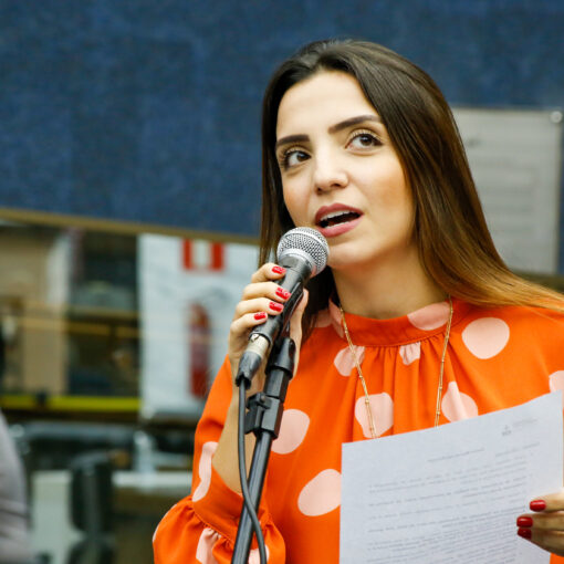 Marcela Trópia discursando em Plenário com blusa laranja