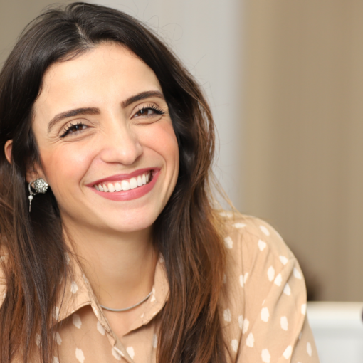 Marcela Trópia sorrindo vestindo blusa bege claro com bolinhas brancas