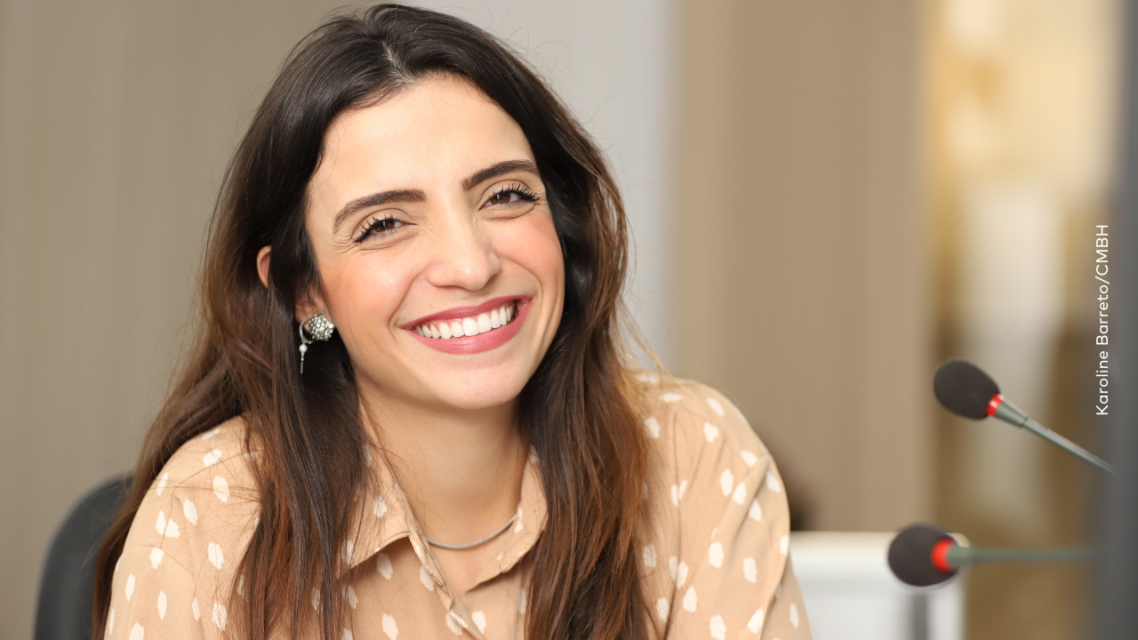 Marcela Trópia sorrindo vestindo blusa bege claro com bolinhas brancas